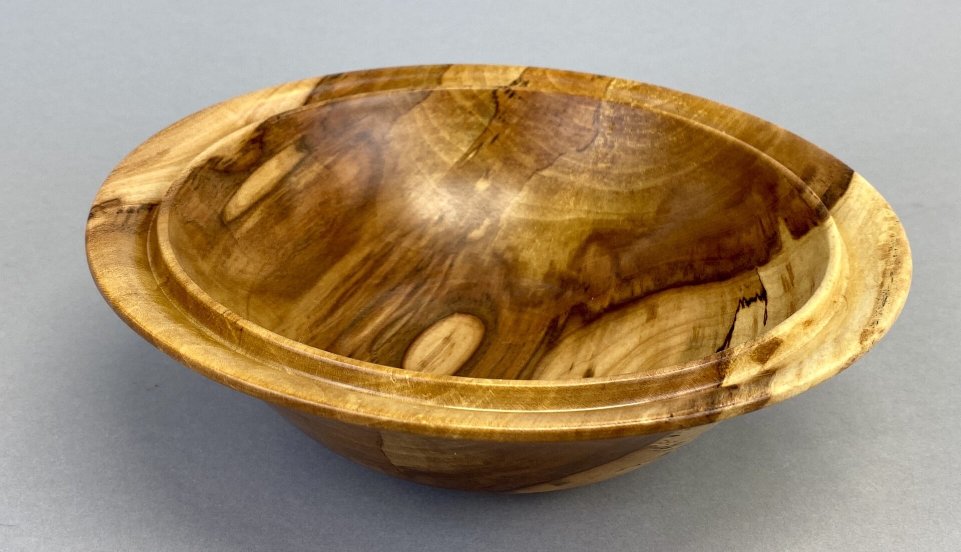 A wooden bowl with a brown surface and some wood grain