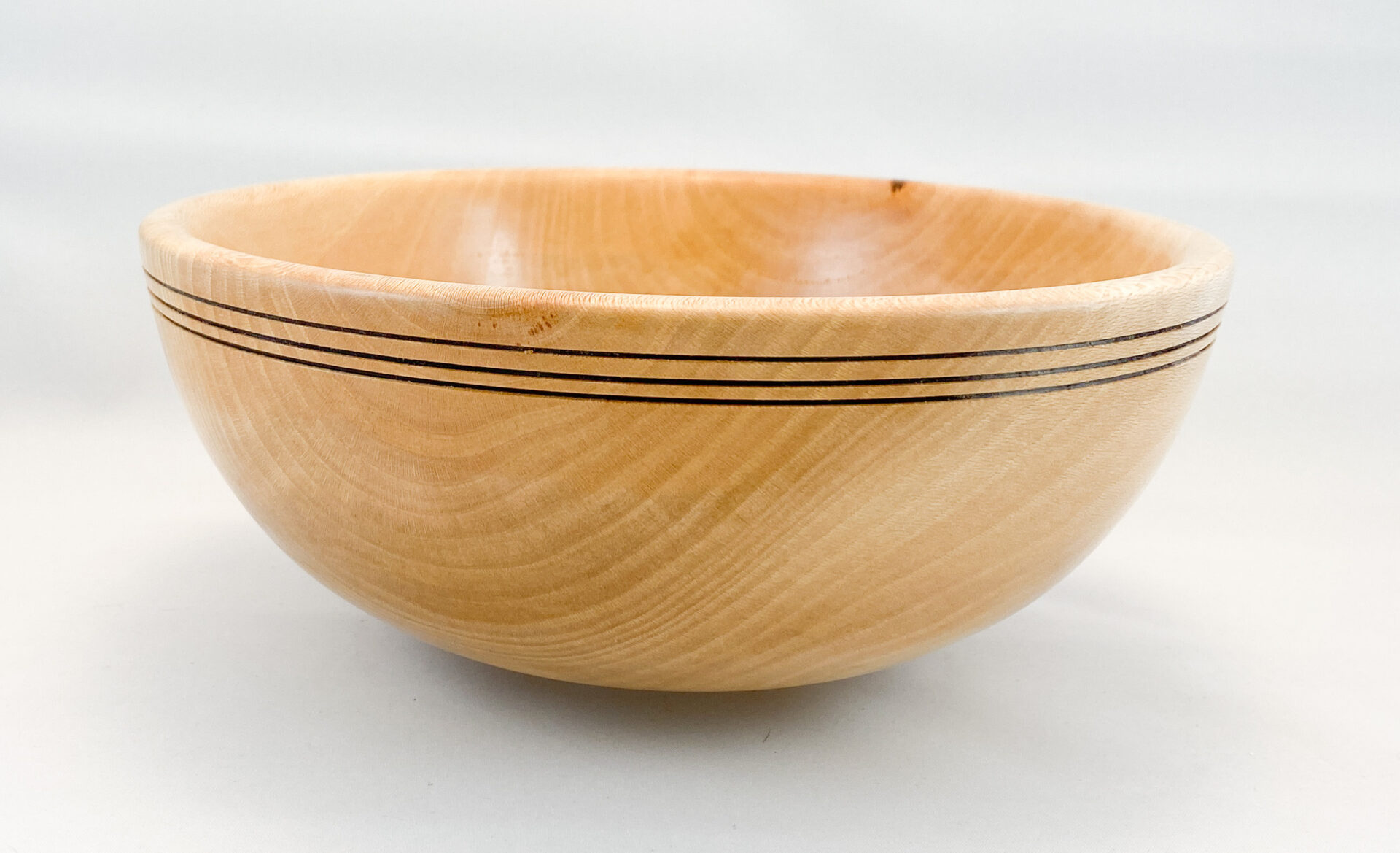 A wooden bowl with black lines on it.