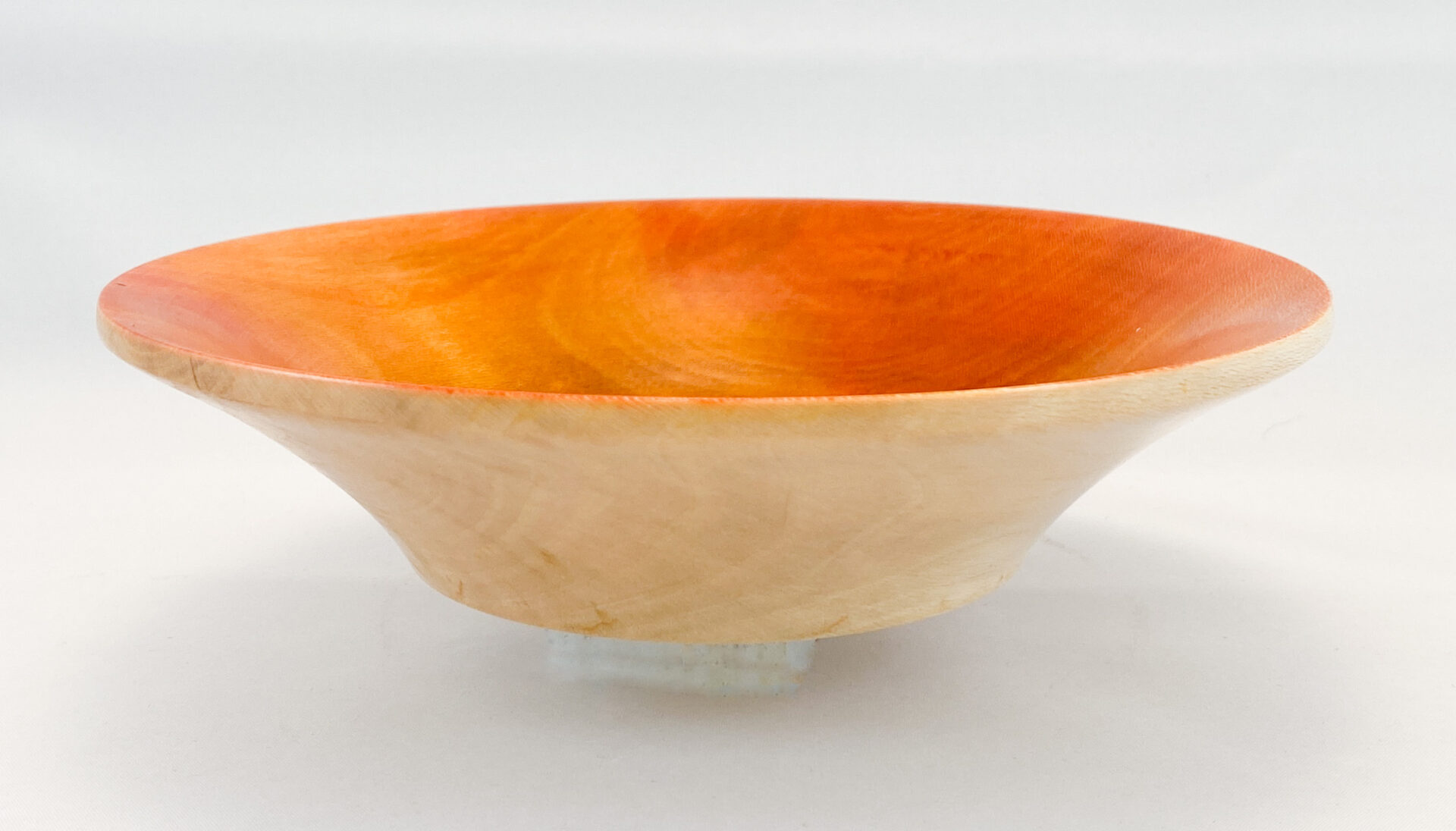 A bowl of wood with orange inside on top.