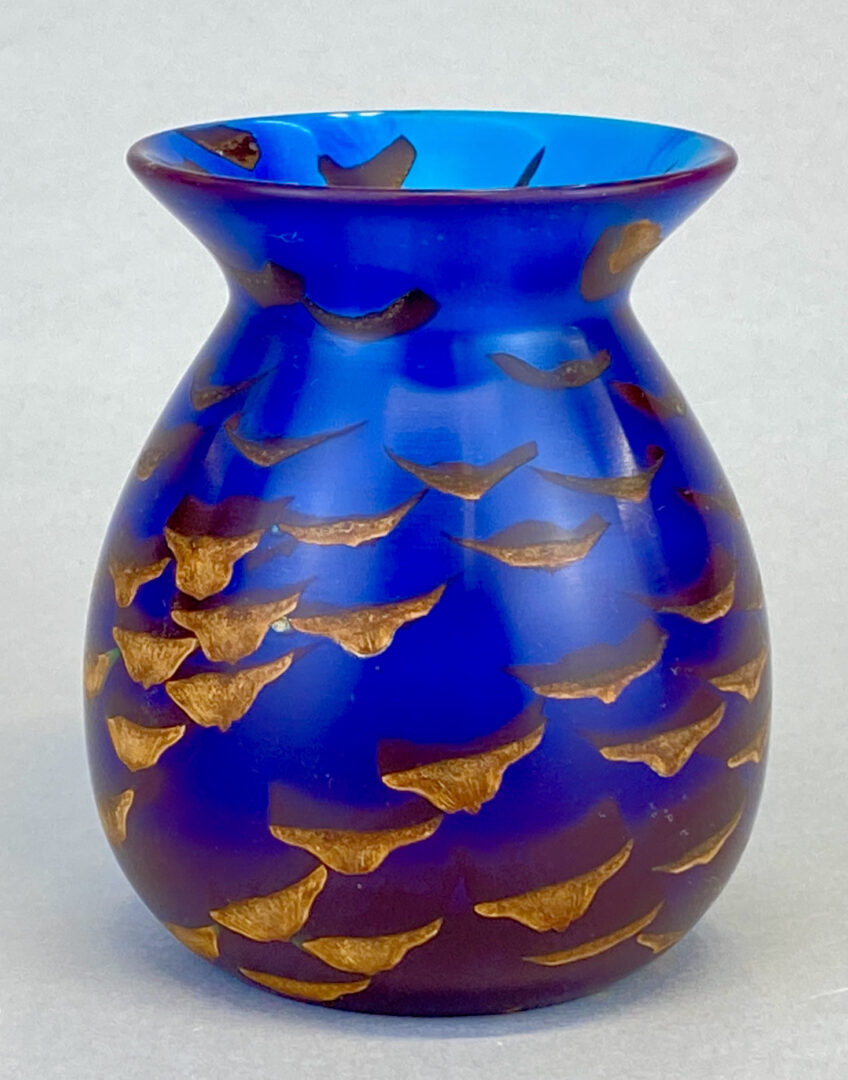 A blue vase with gold leaves on it.