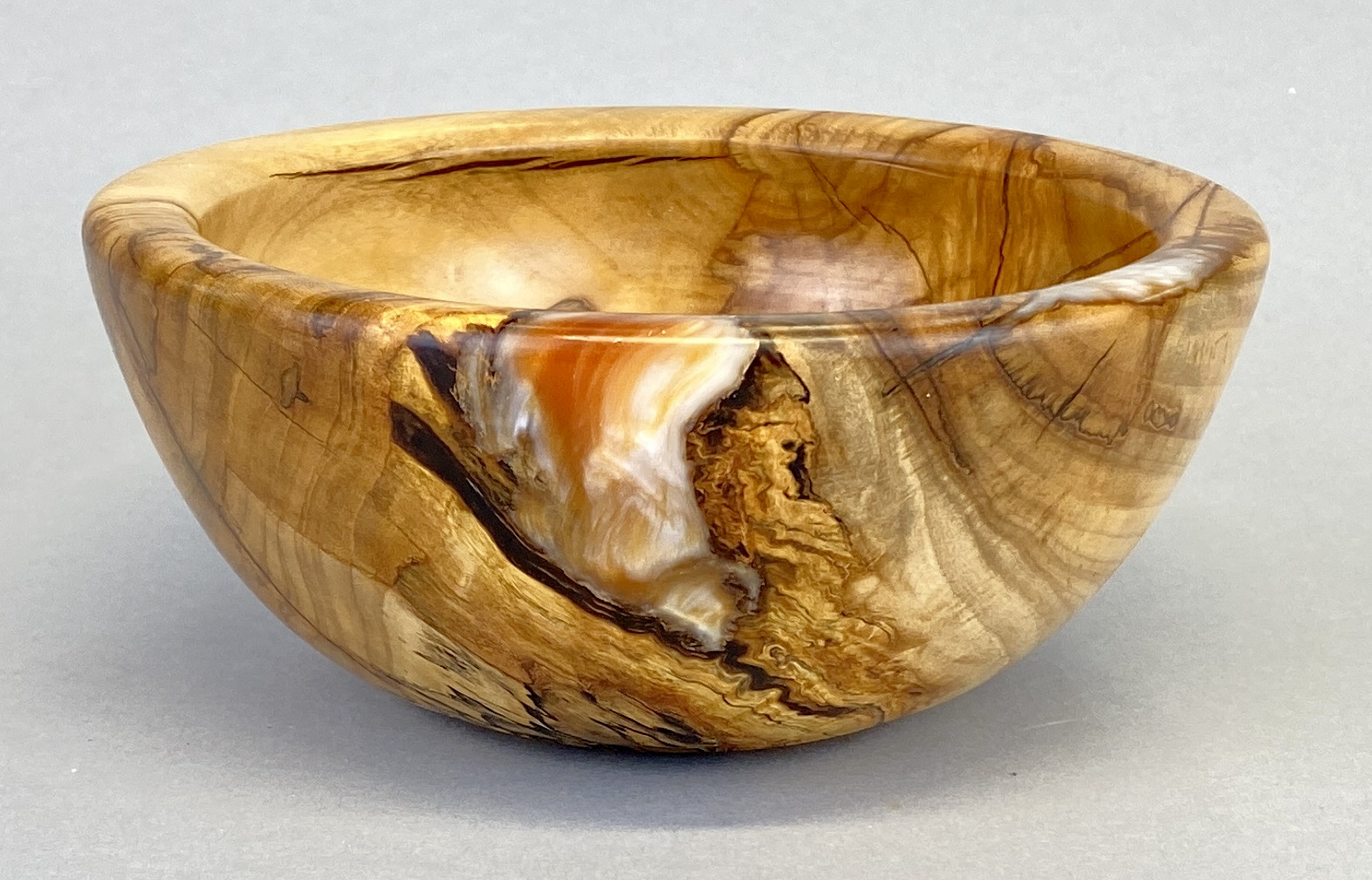 A wooden bowl with a brown and orange design.