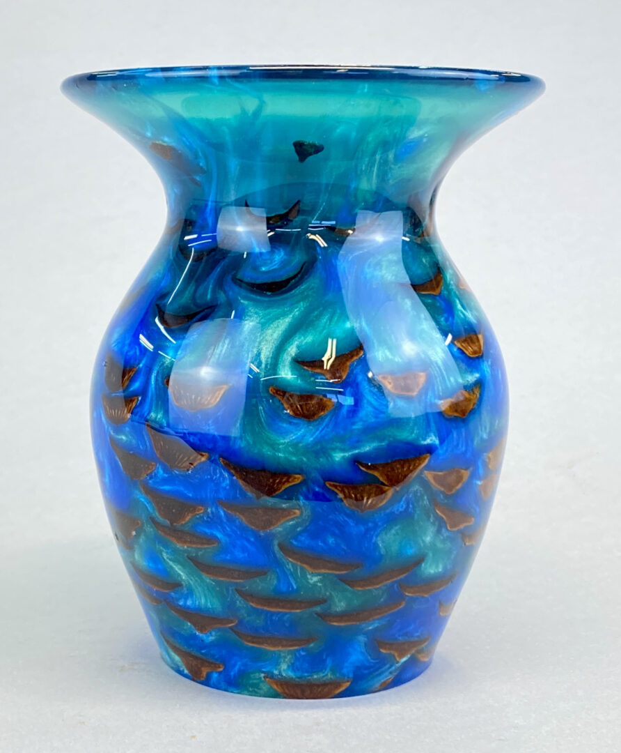 A blue vase with brown and black spots on it.