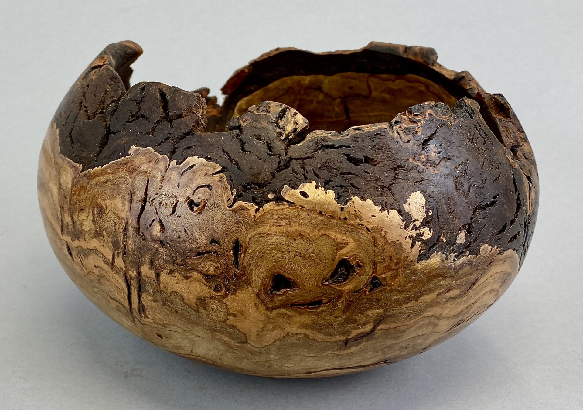 A wooden bowl with cracked surface and brown color.