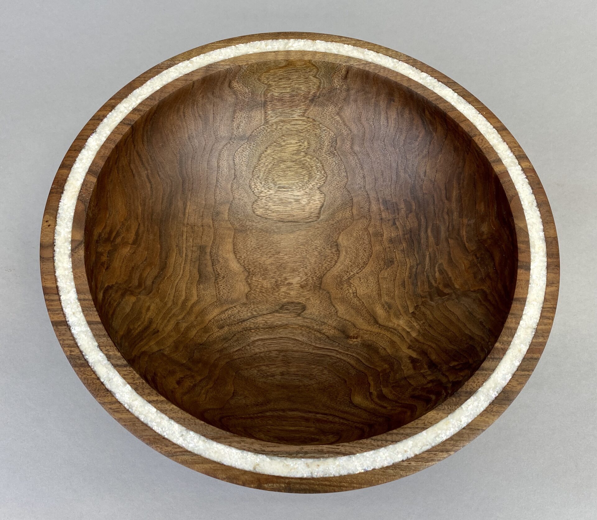 A wooden bowl with white trim on top of a table.