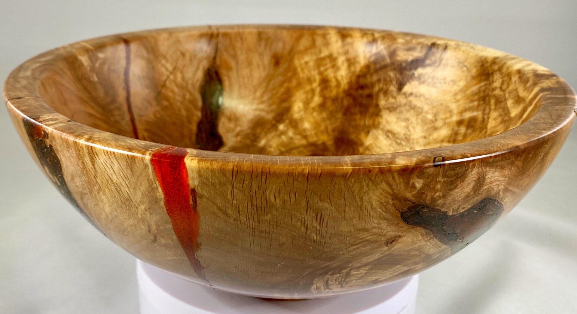 A bowl made of wood with red and orange paint.