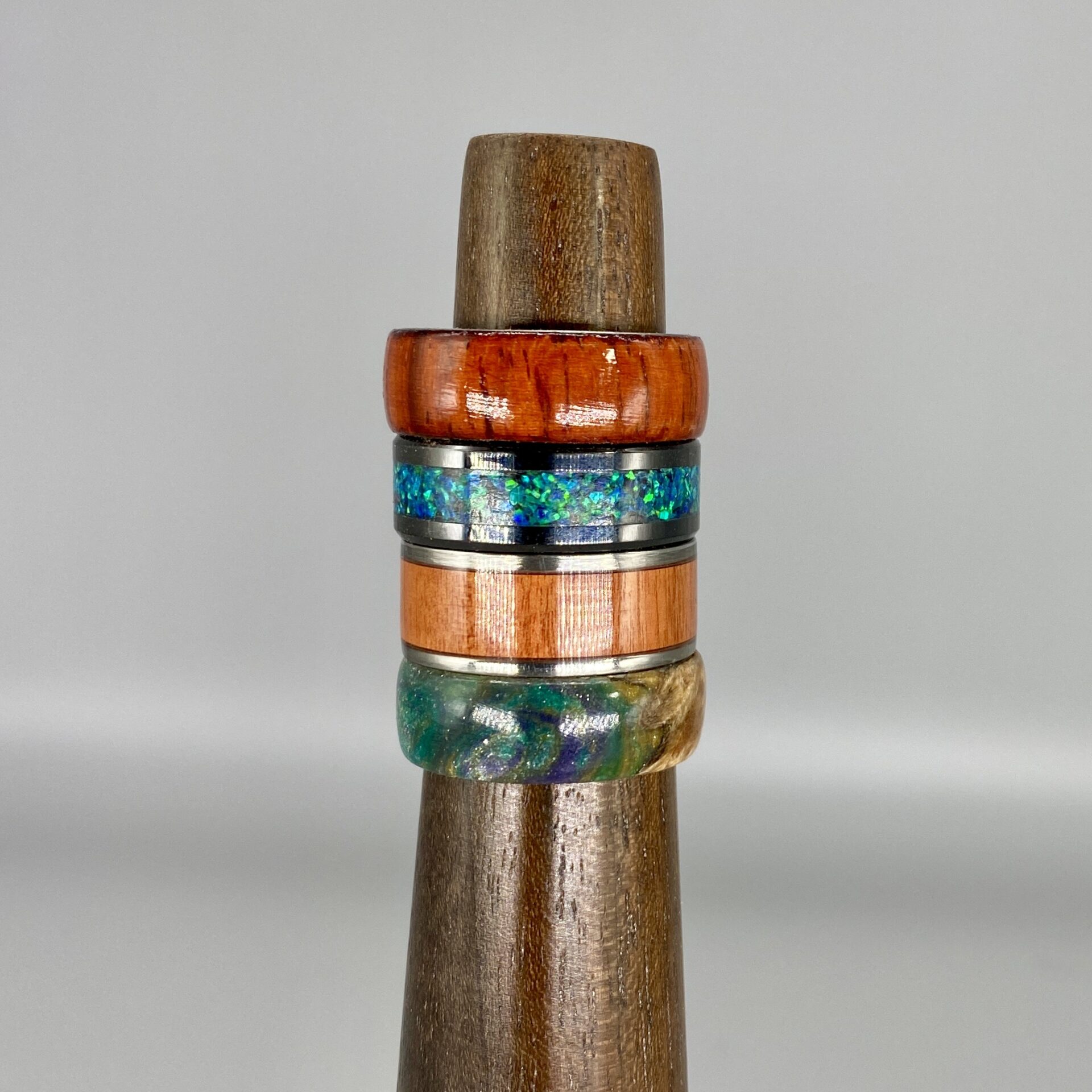 A wooden ring holder with different colored rings on it.