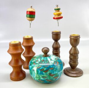 A group of wooden candlesticks and a blue jar.