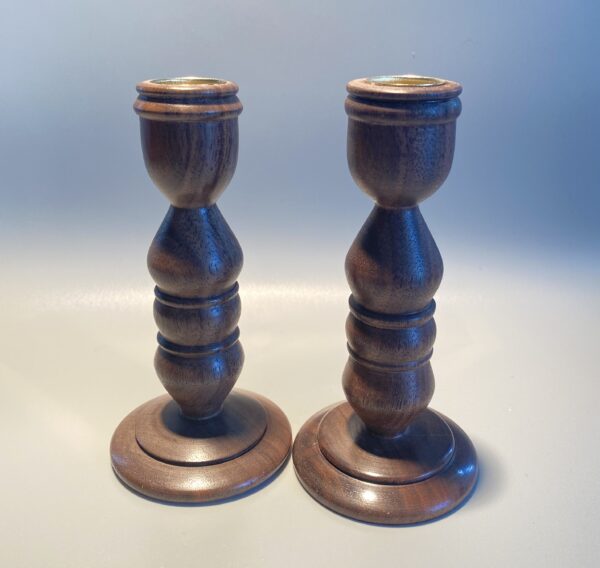 A pair of wooden candlesticks with a gold top.