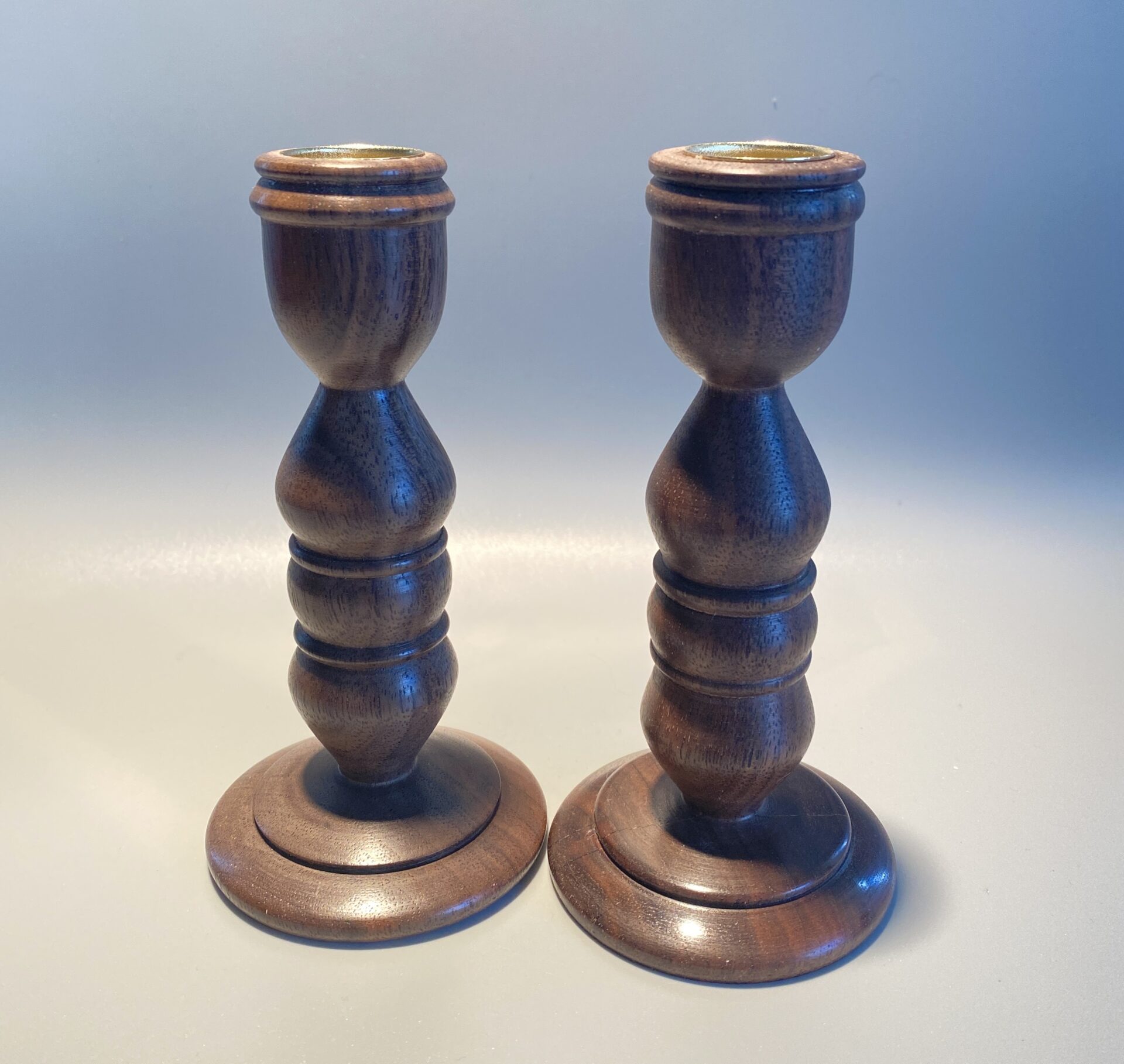 A pair of wooden candlesticks with a gold top.