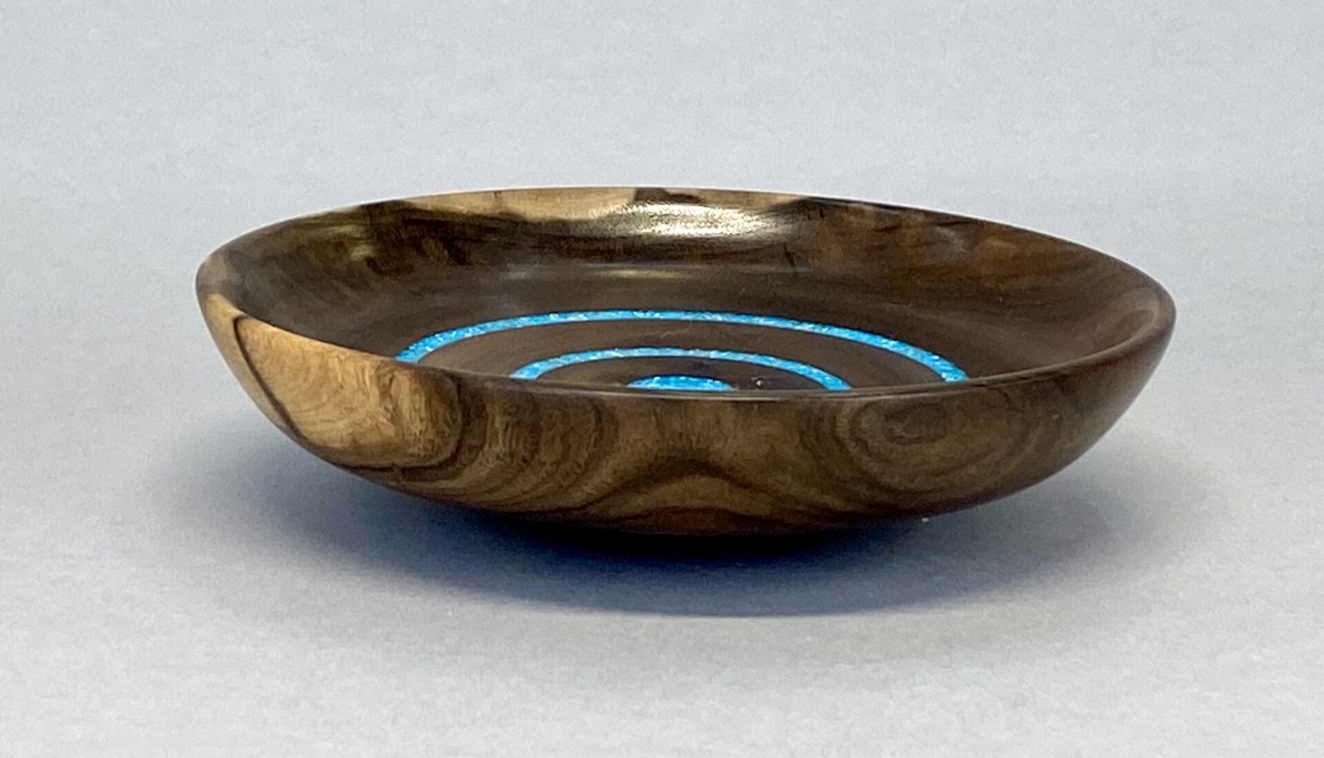 A wooden bowl with blue circles on it.