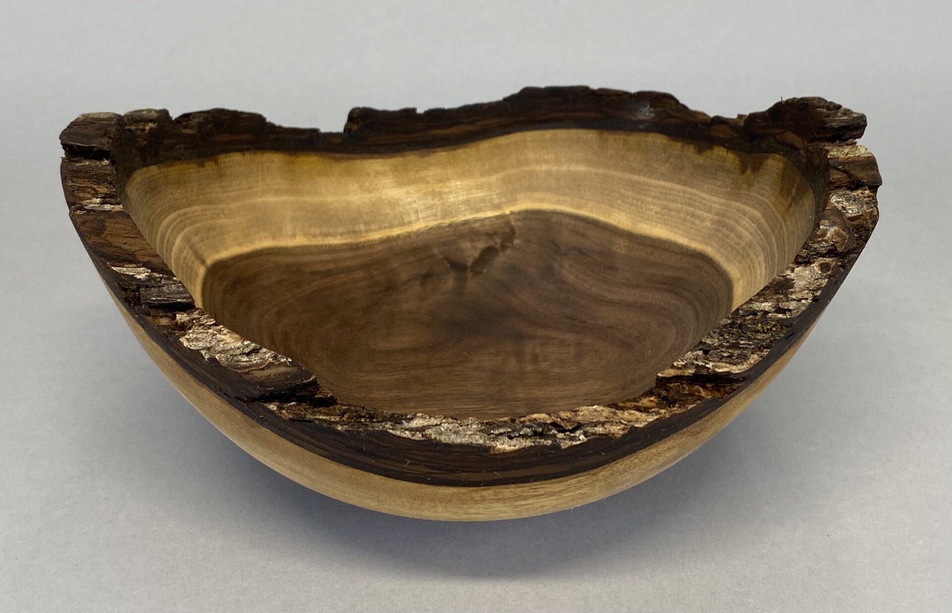 A wooden bowl with a tree trunk and bark on it.