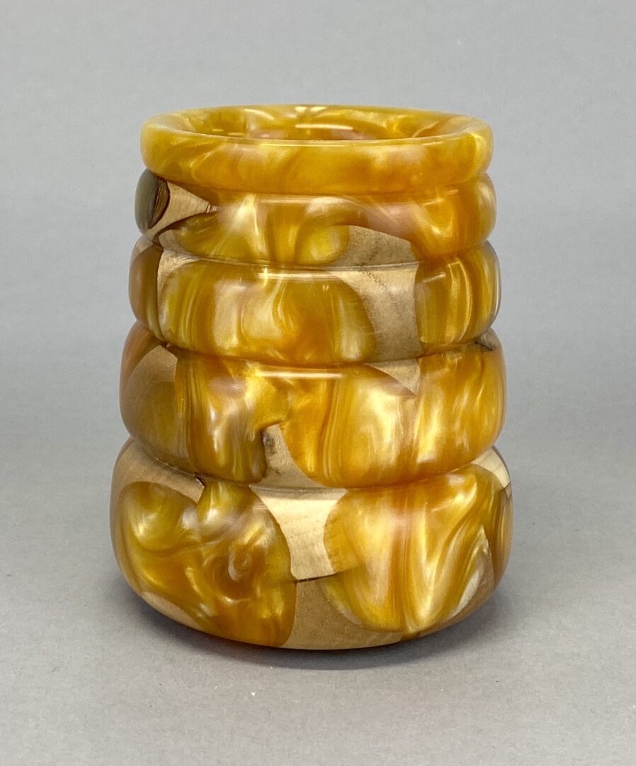 A stack of four yellow and white bracelets.