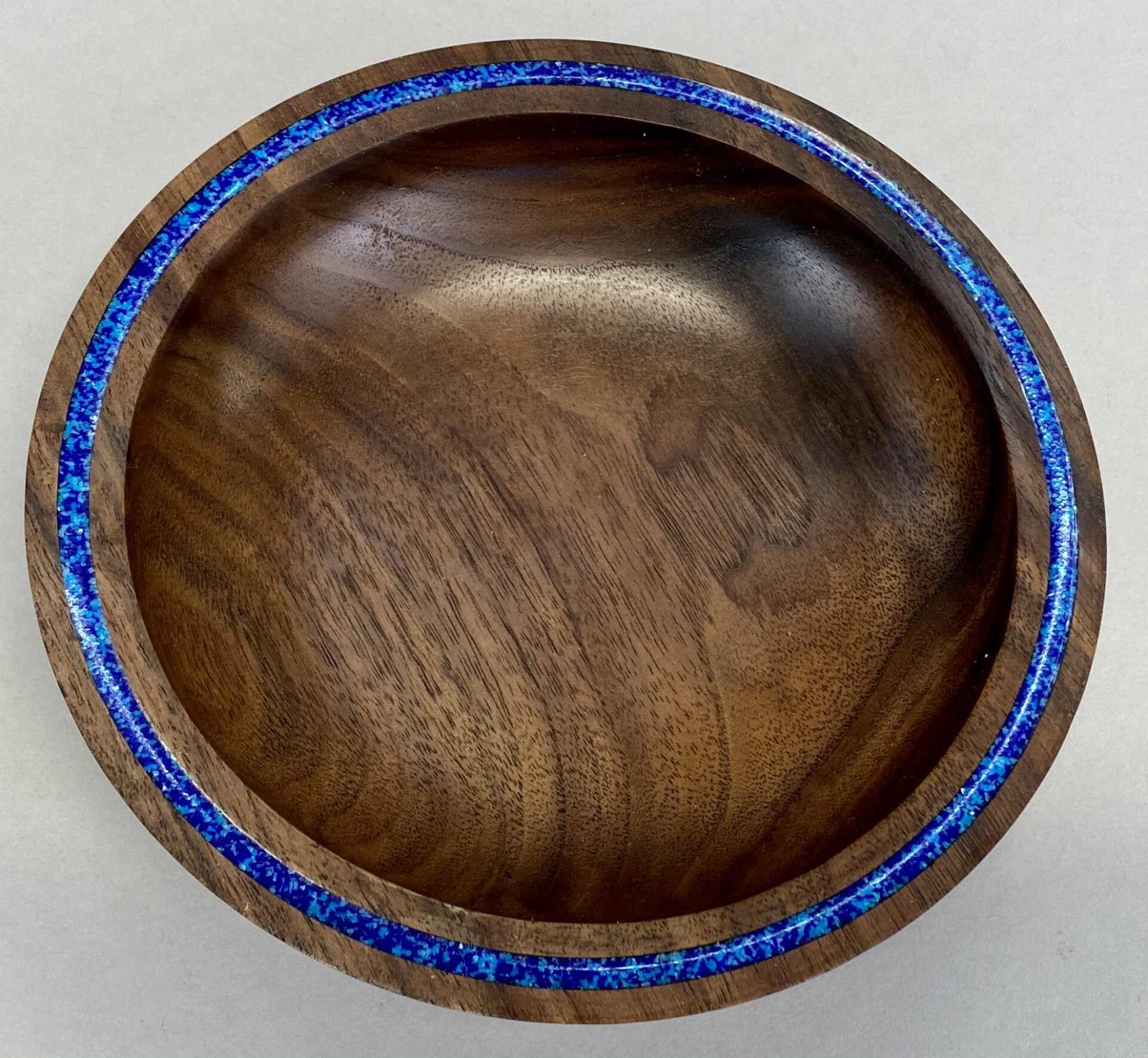 A wooden bowl with blue inlay on top of it.