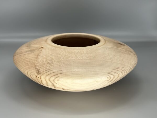 A wooden bowl with a brown rim on top of a table.