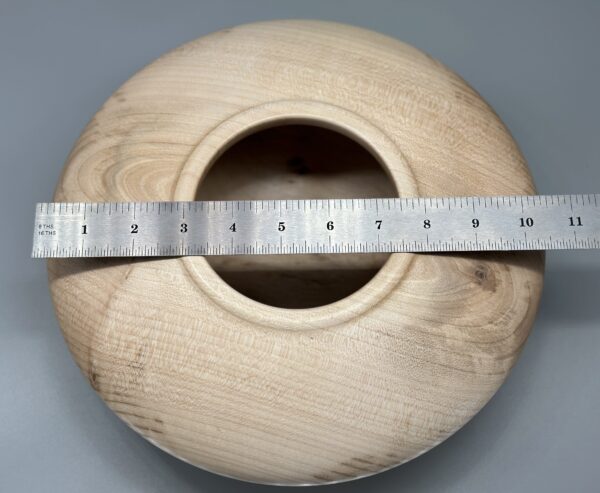 A wooden bowl with a metal ruler around it.
