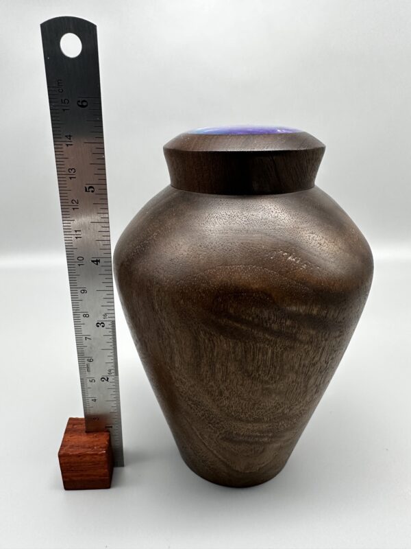 A large vase next to a ruler and a wooden block.