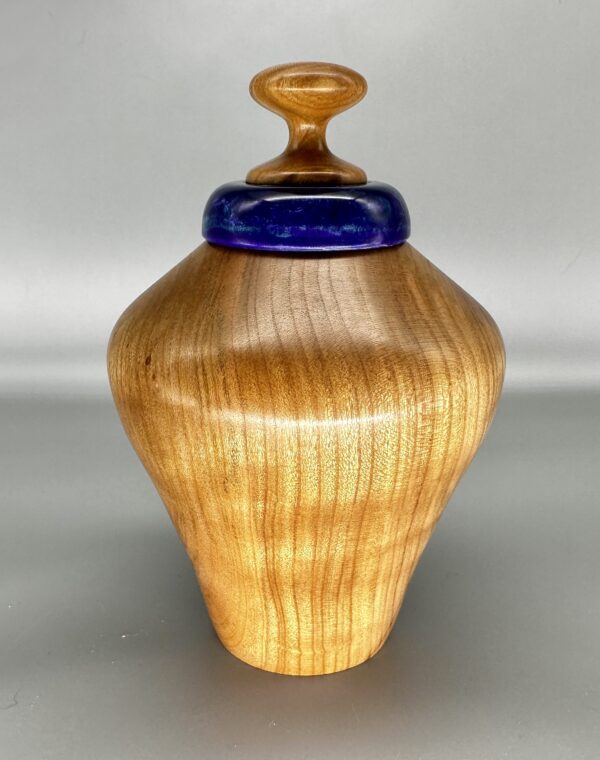 A wooden vase with blue top on the bottom.