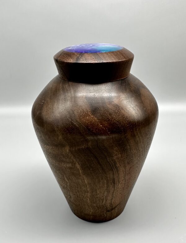 A wooden urn with a blue light on top of it.