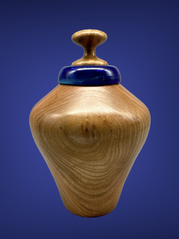 A wooden vase with blue top on a table.