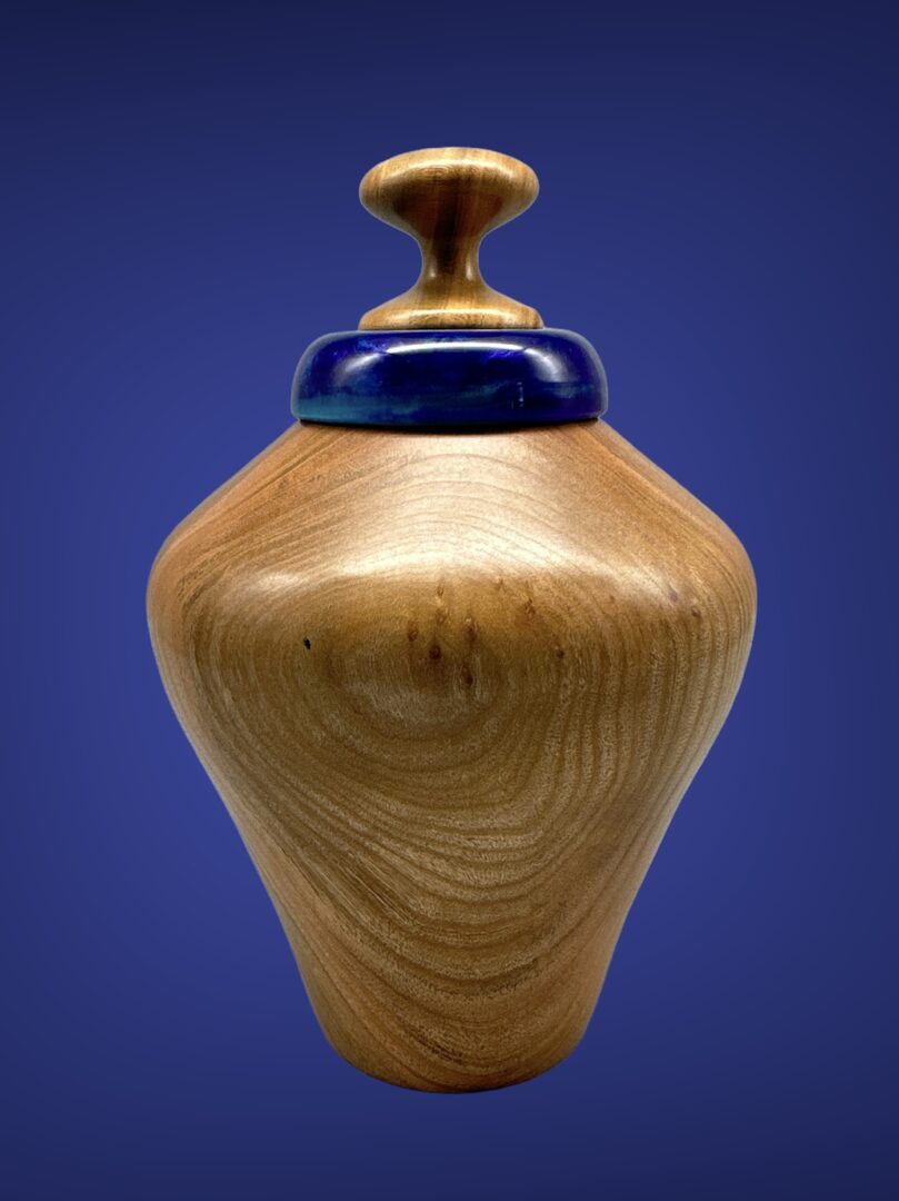 A wooden vase with blue top on a table.