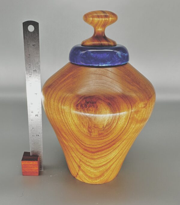 A wooden vase with a blue lid and a ruler