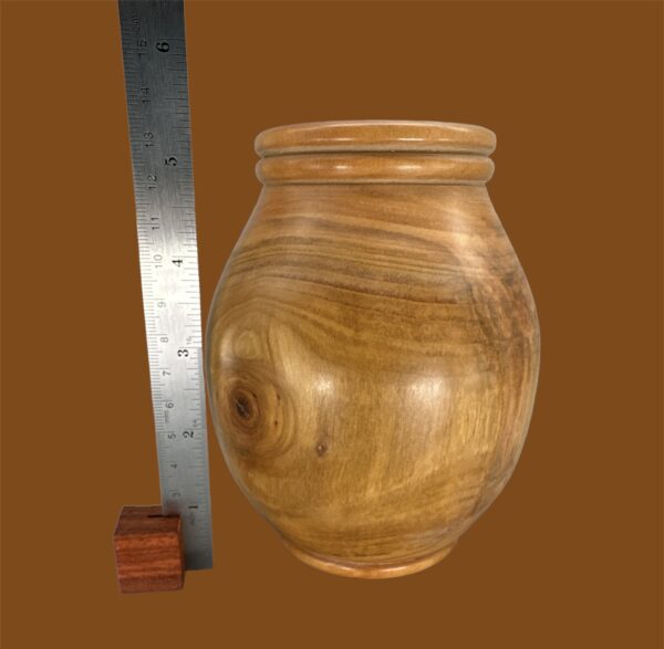 A wooden vase with a ruler next to it