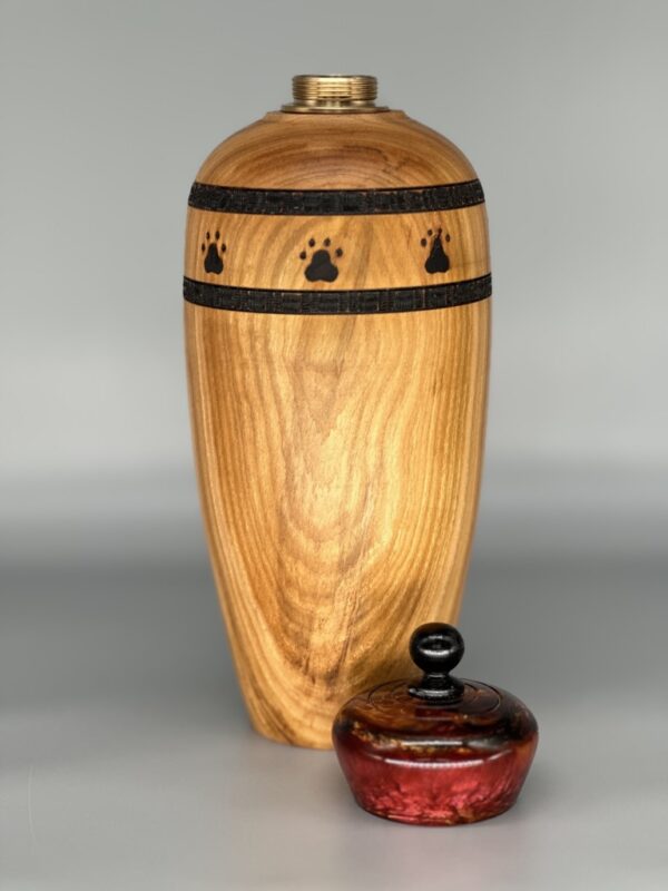 A wooden urn with paw prints on the side and a red container.