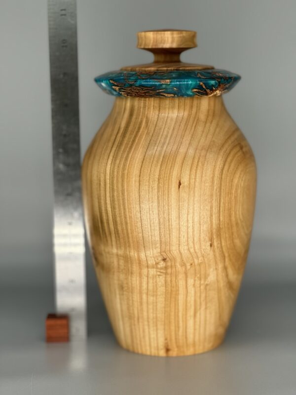 A wooden vase with a glass lid and a knife.