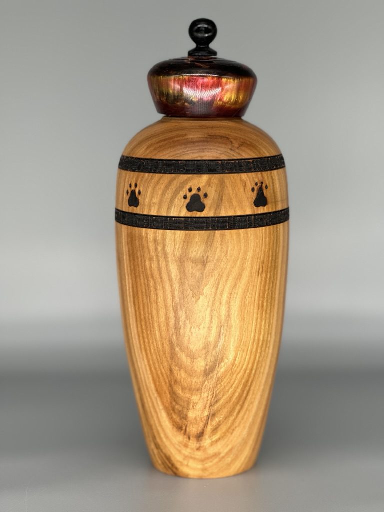 A wooden vase with black and brown designs on it.