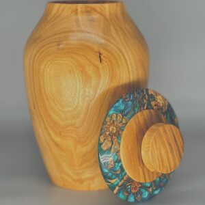 A wooden vase with a lid and flowers on it.