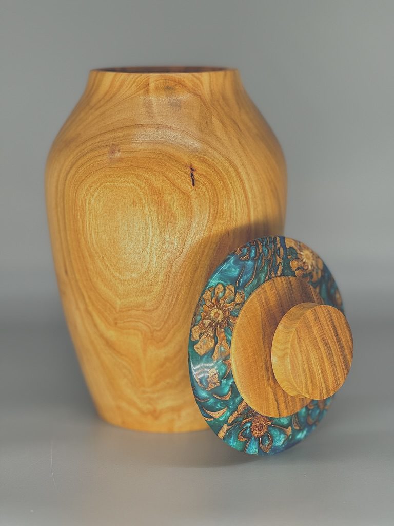 A wooden vase with a lid and flowers on it.