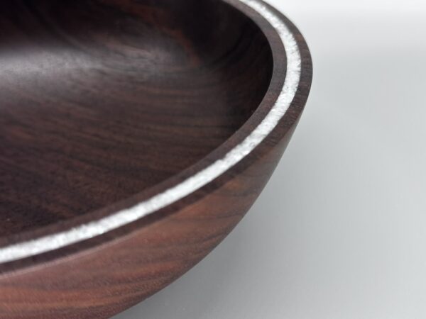 A wooden bowl with metal trim on top of a table.