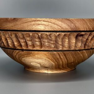 A wooden bowl with a carved design on the side.