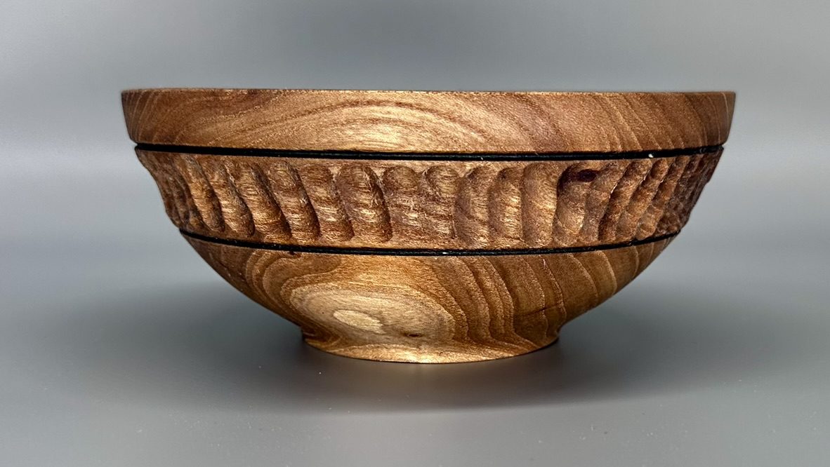 A wooden bowl with a carved design on the side.