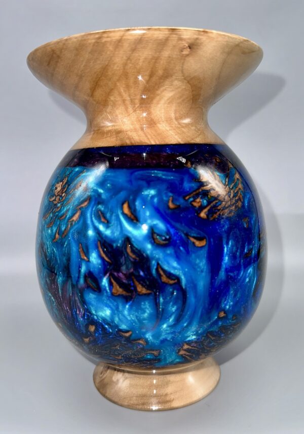 A blue vase with gold and black swirls on it