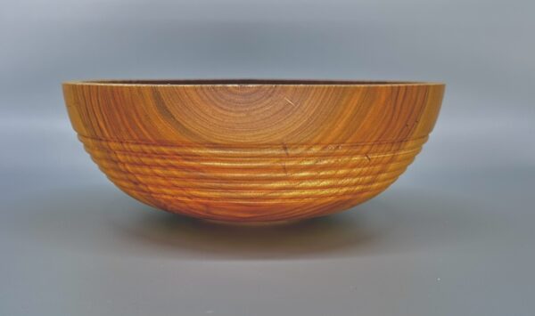 A wooden bowl with a pattern of lines on it.