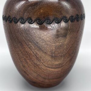 A wooden vase with black lines on the side.